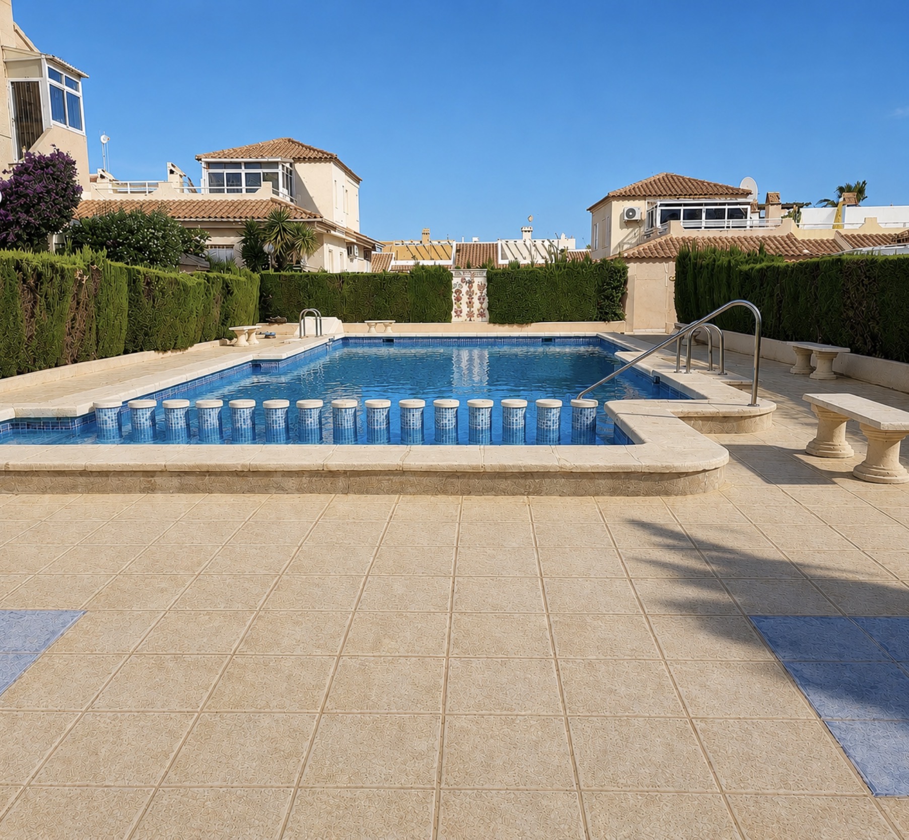 Privat pool med solstolar och palmer